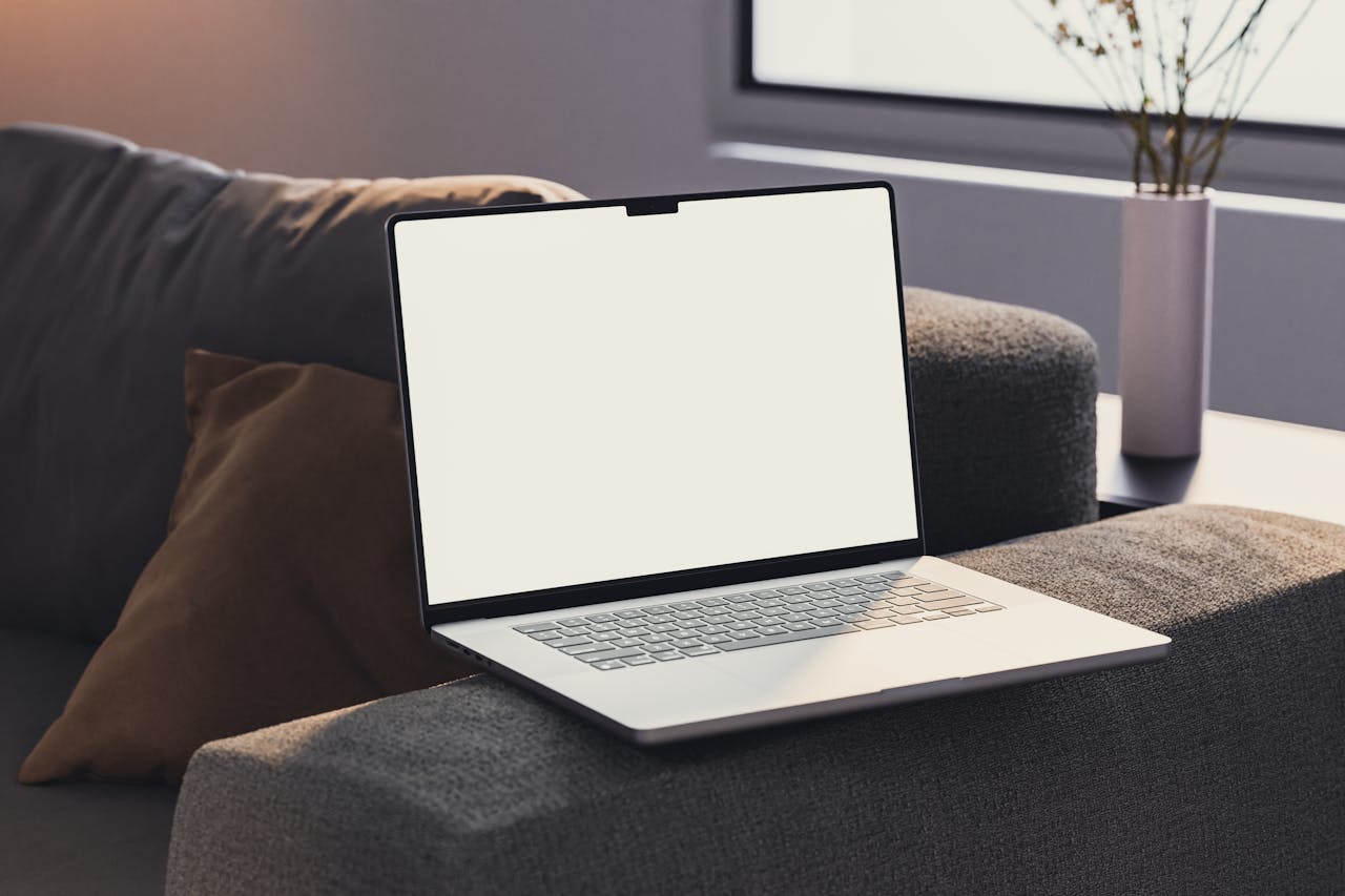 A clean and simple laptop with a blank screen rests on a sofa, ideal for mockups.
