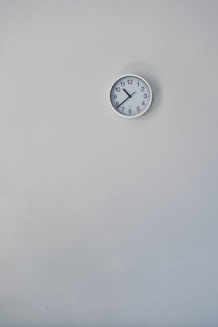 A minimalist white wall clock against a plain background, showcasing simple design.