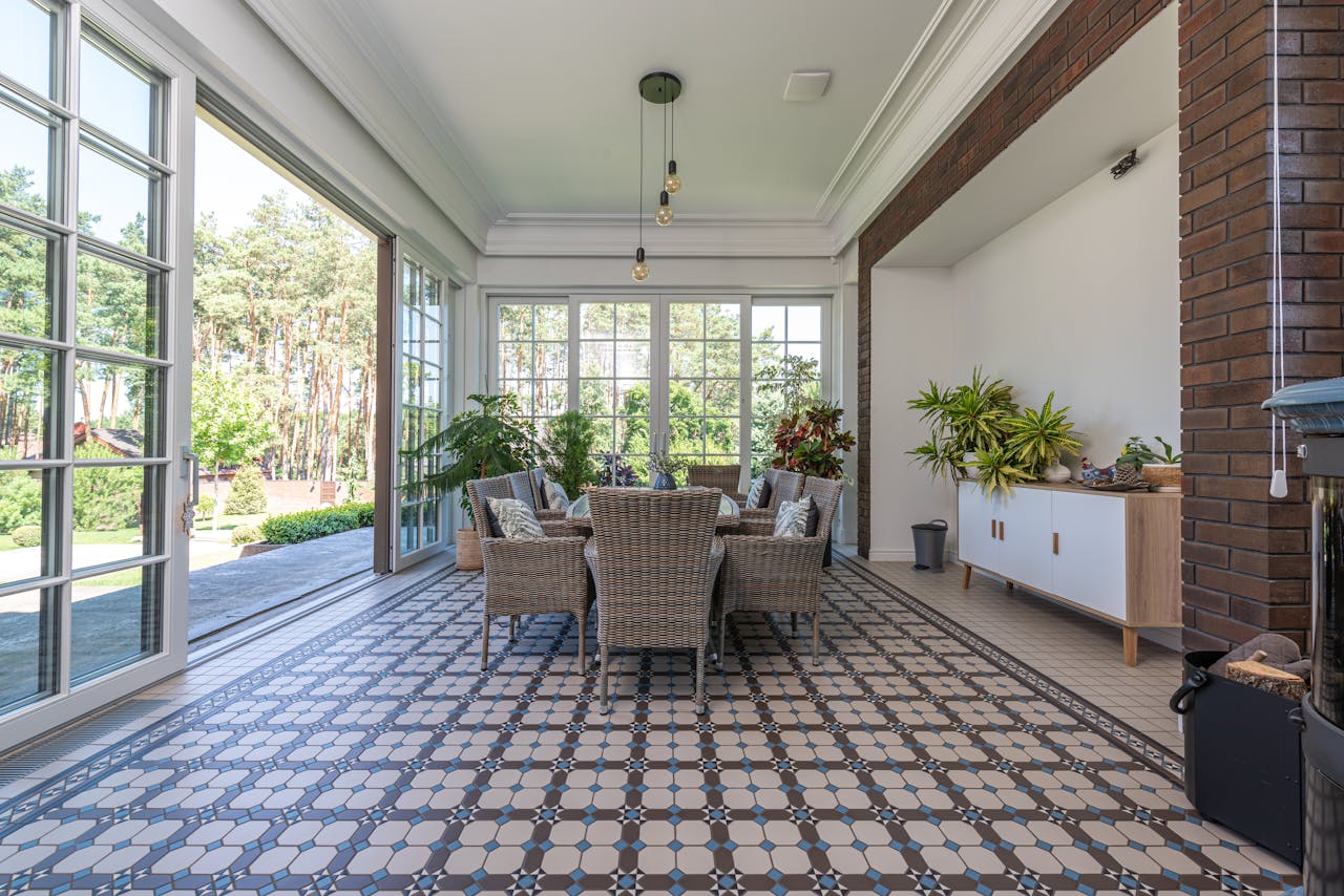 Bright sunroom with wicker chairs and patterned tile floor, ideal for relaxation.